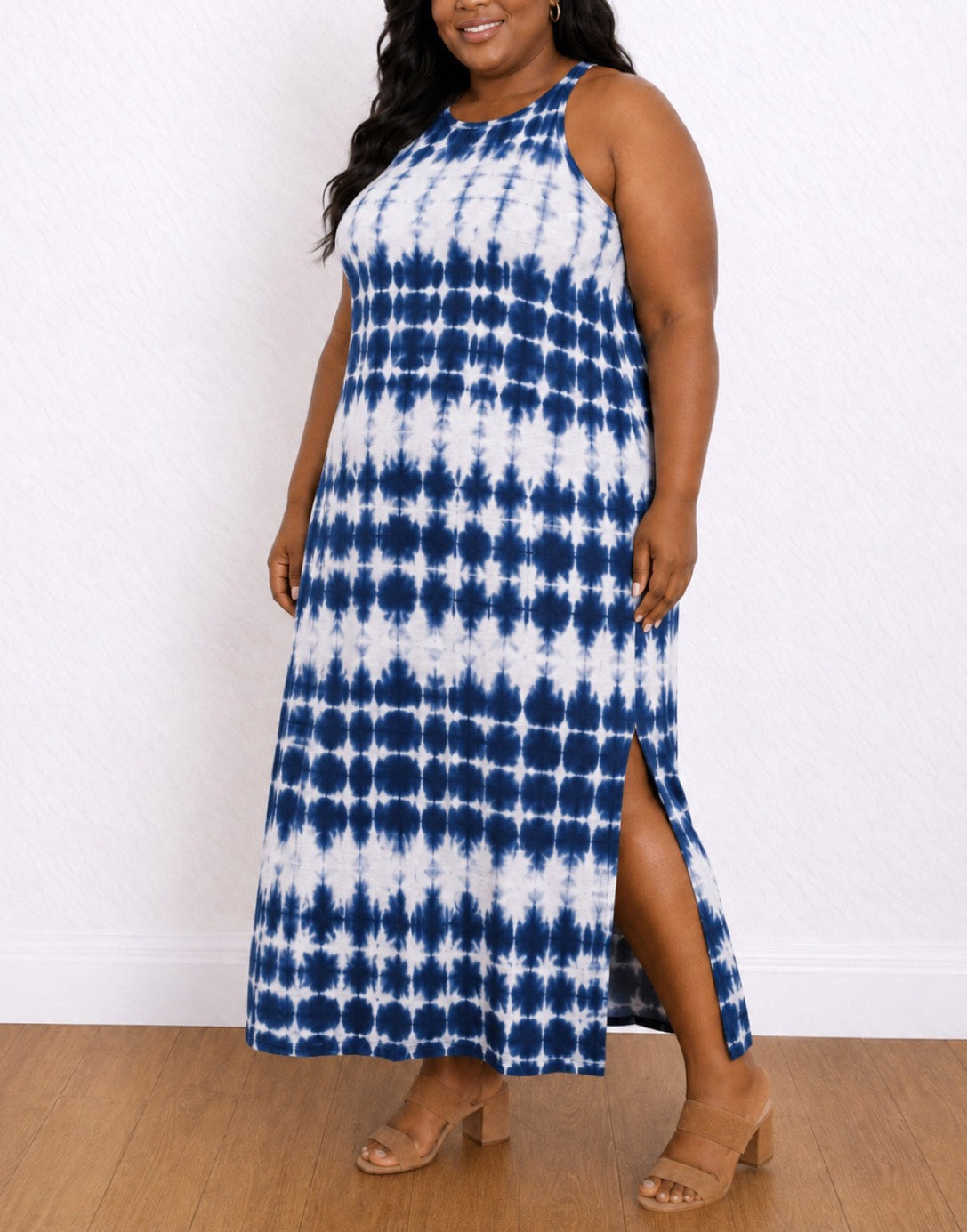 Side view of a woman modeling a Sleeveless Maxi Tank Dress with a blue and white tie-dye pattern and a side slit, standing against a white wall on a wood floor.