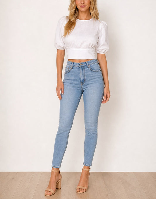 Woman wearing a white Puff Sleeve Open Back Tie Crop Blouse and light blue jeans against a white background.