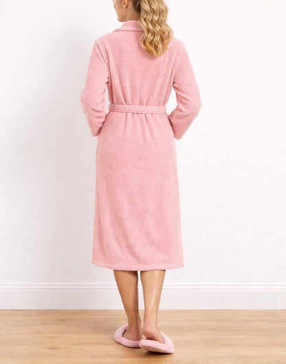 Back view of woman wearing a pink Shawl Collar Bathrobe and matching slippers on a wooden floor.