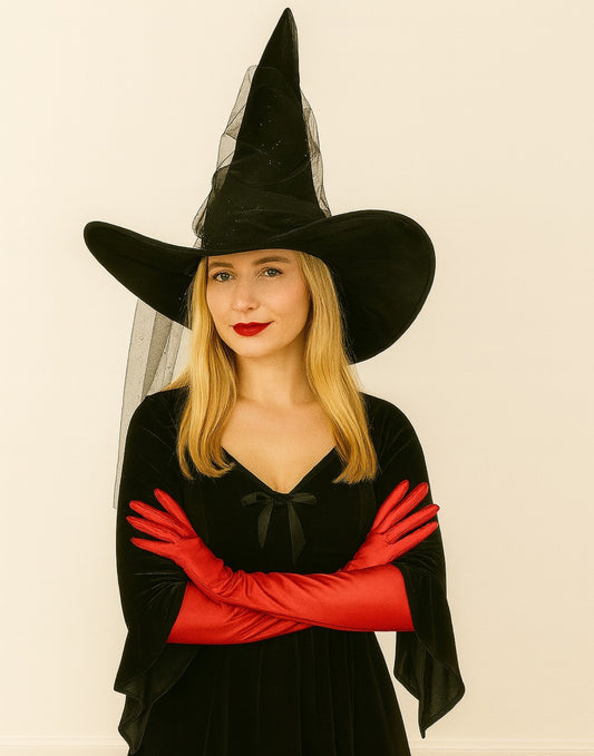 Person wearing a black witch hat with a veil and red Witch Long Gloves on a beige background
