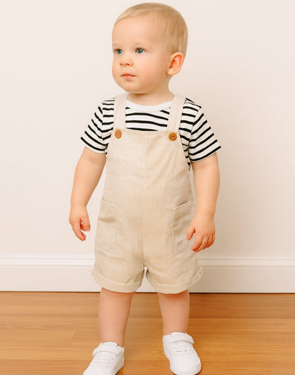 Child wearing a striped shirt and beige Patch Pocket Overall Romper standing on a wooden floor.