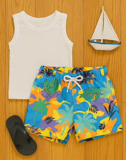 White tank top and colorful tropical Baby Boy Swim Shorts on a wooden surface with a toy sailboat.