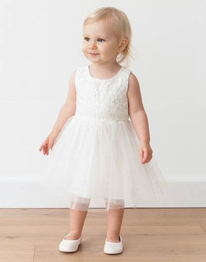 Baby in a white Sleeveless Party Dress with a wooden floor background