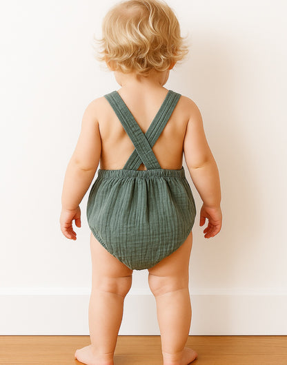 Back view of baby wearing a green Patch Pocket Overall Romper in front on a plain white background.