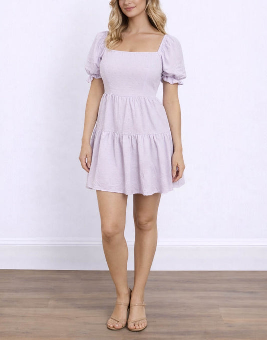 Woman wearing a light purple Puff Sleeve Mini Dress with puff sleeves against a white background