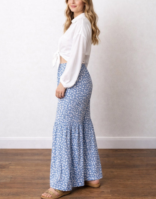 Side view of woman wearing a white tie front blouse with blue patterned Bell Bottom Pants against a plain white background.