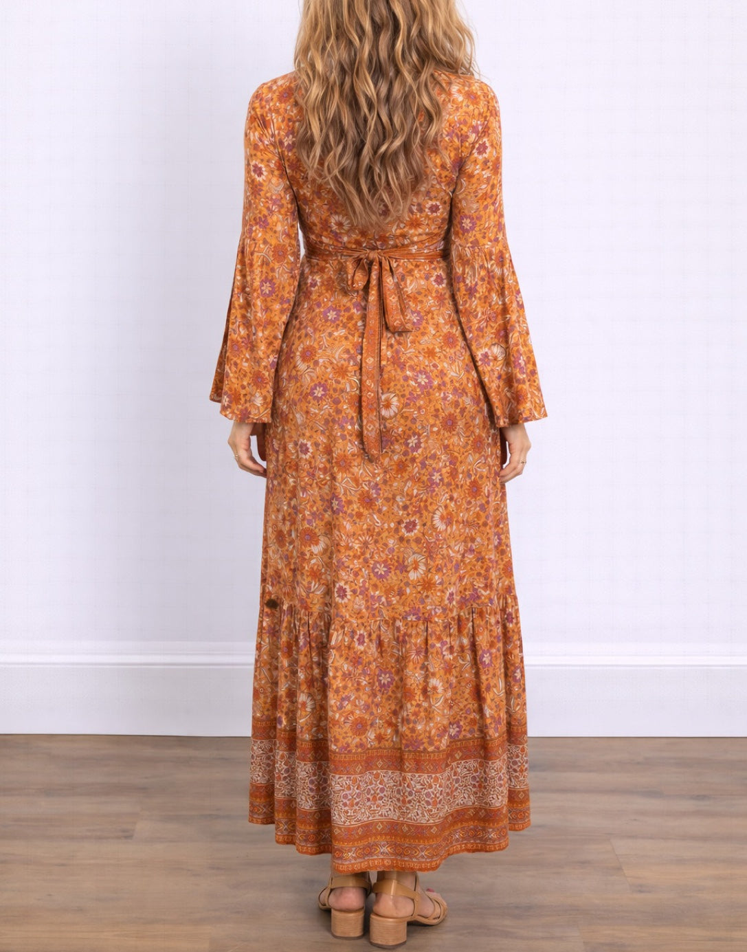Back view of woman wearing an orange floral Bell Sleeve Tie Front Wrap Maxi Dress against a white background.