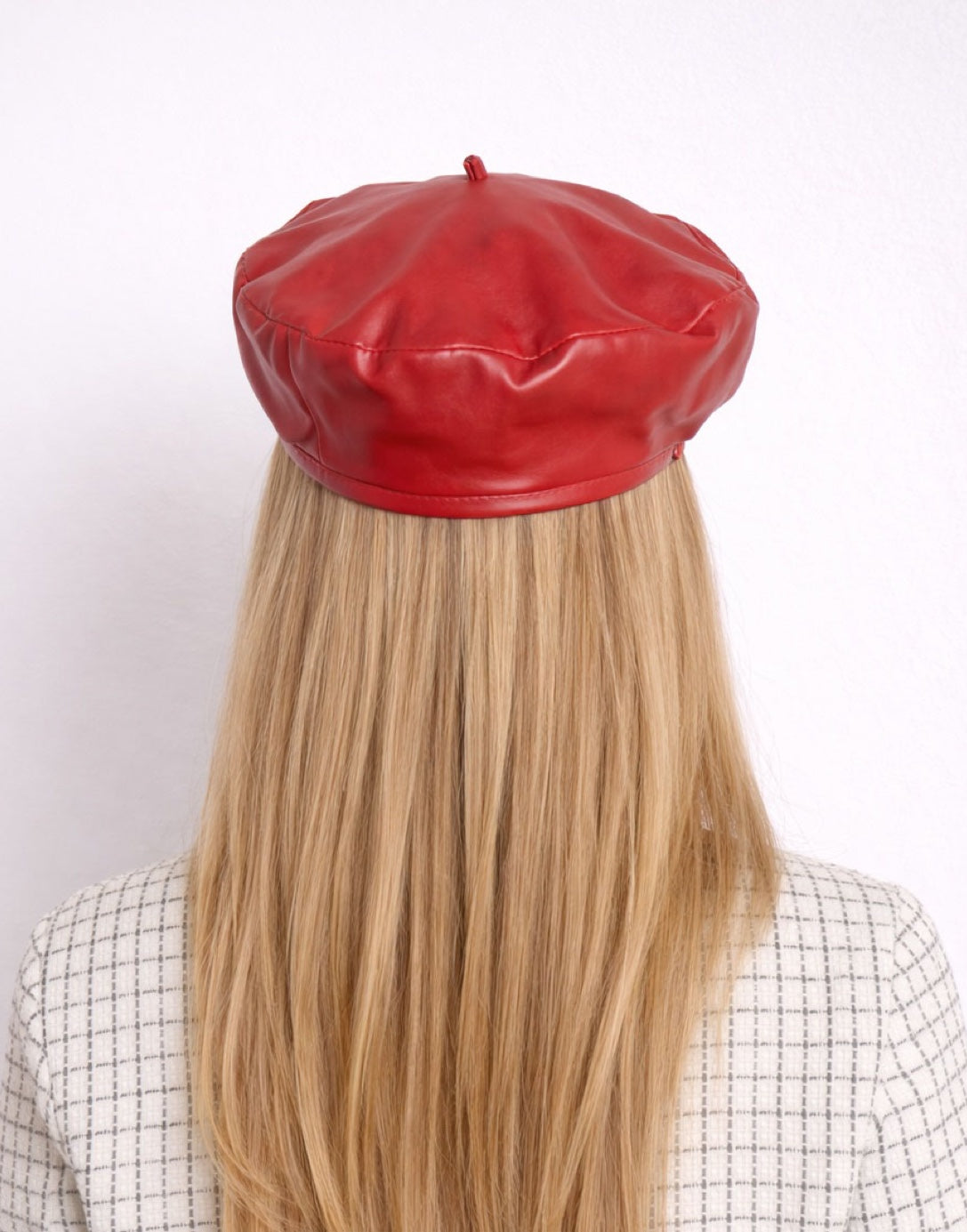 Back view of woman wearing a red leather Beret Hat against a white background.