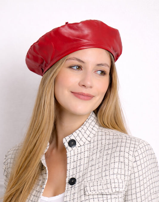 Side view of woman wearing a red leather Beret Hat against a white background.