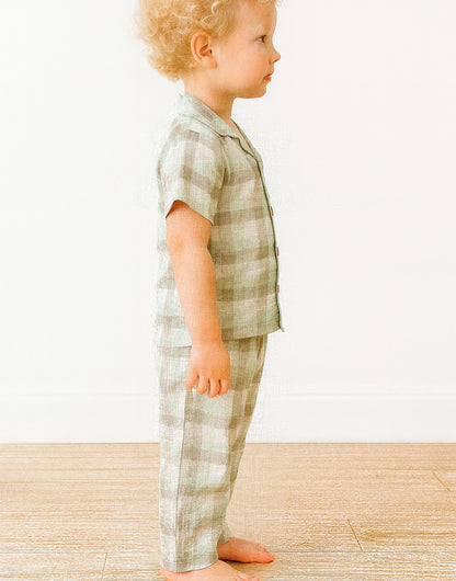 Side view of child wearing a green plaid pajama set against a white background.