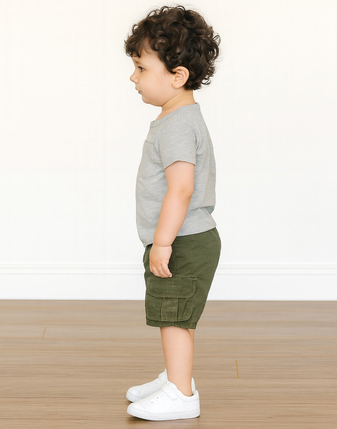 Side view of Pocket Patched Tee child wearing a gray shirt and green shorts on a white background.