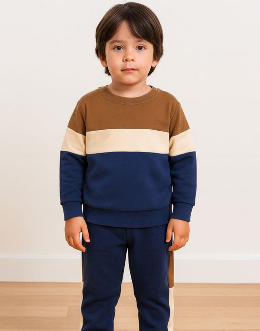 Boy wearing a brown, beige, and navy striped sweater with matching sweatpants on a plain background