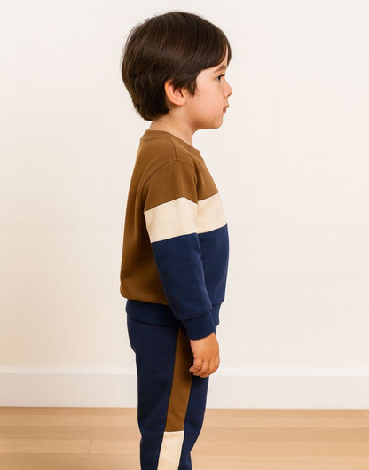 Side view of child wearing a brown, beige, and navy striped sweater with matching sweatpants on a plain background.