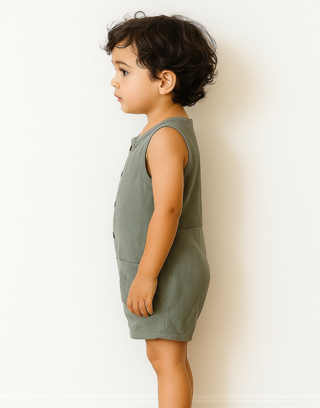 Child wearing a green Sleeveless Button Down Romper against a white background