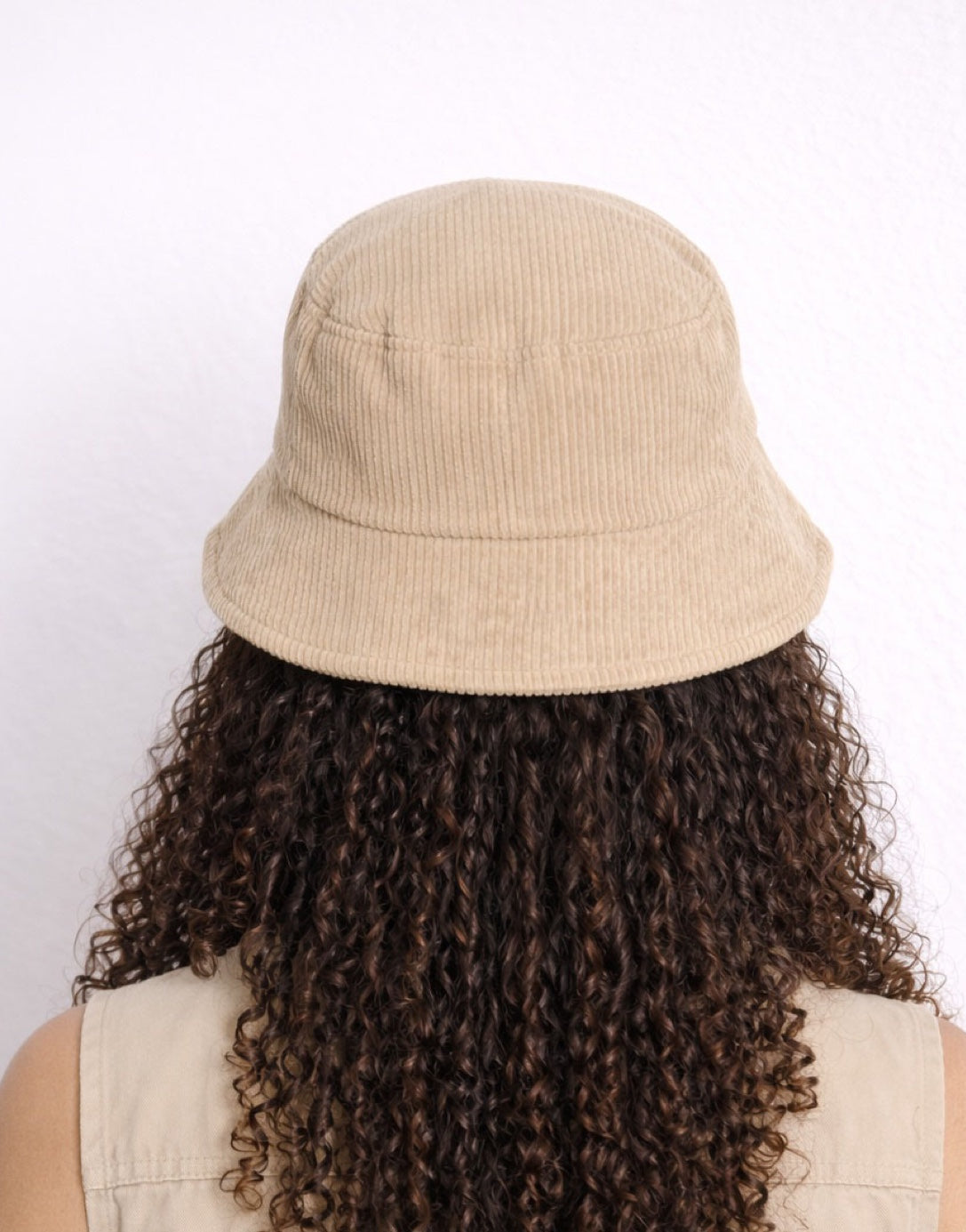 Back view of woman wearing a beige Bucket Hat and matching shirt against a white background.