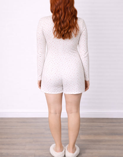 Back view of woman wearing a white Button Front Knit Sleep Romper with a subtle pattern on a plain background.