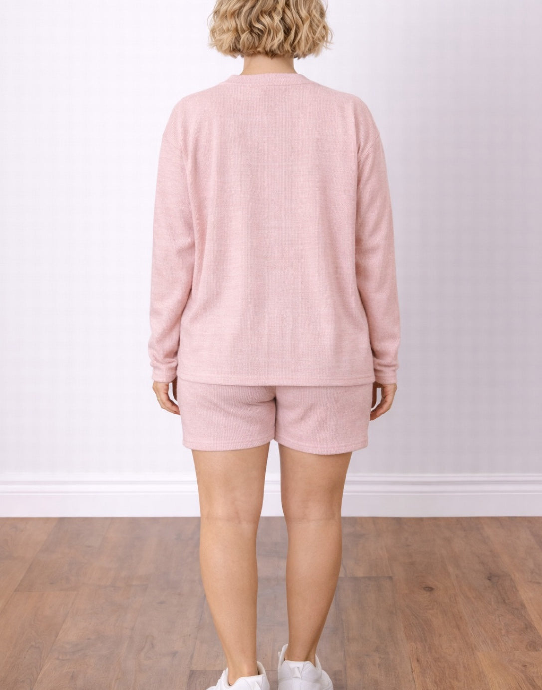 Back view of woman wearing a pink Cardigan with Crop Top and Shorts Set on a plain background.