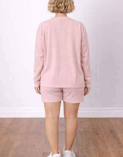 Back view of woman wearing a pink Cardigan with Crop Top and Shorts Set on a plain background.