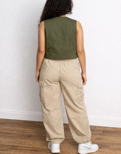 Front view of woman wearing a green Cargo Pocket Vest and beige cargo pants against a plain background.