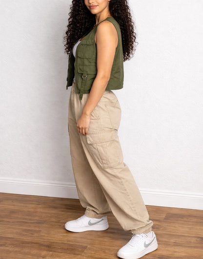 Side view of woman wearing a green Cargo Pocket Vest and beige cargo pants against a plain background.