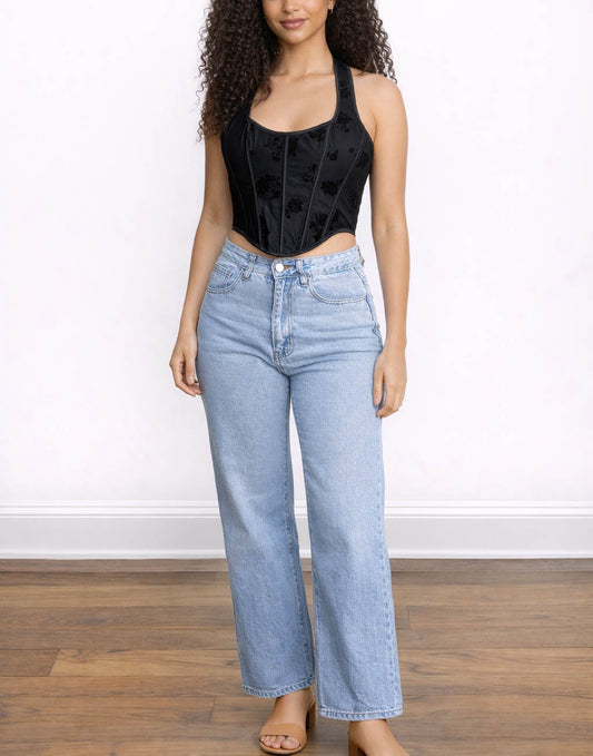 Woman wearing a black sleeveless Corset Halter Top and light blue jeans on a white background.
