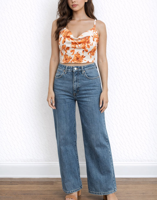 Woman wearing a floral Cowl Neck Cami Crop Top with orange flowers on a plain background.