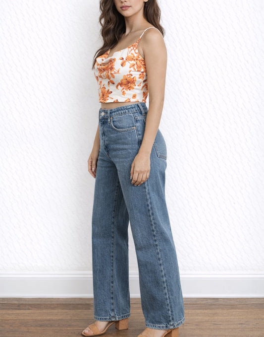 Side view of woman wearing a floral Cowl Neck Cami Crop Top with orange flowers on a plain background.