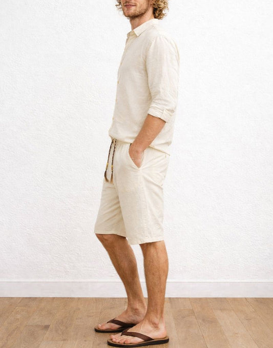 Side view of man wearing a beige shirt and Drawstring Knee Length Shorts against a white wall.
