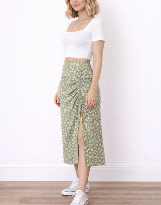 Side view of woman wearing a white crop top and green floral Drawstring Ruched Midi Skirt on a plain background.