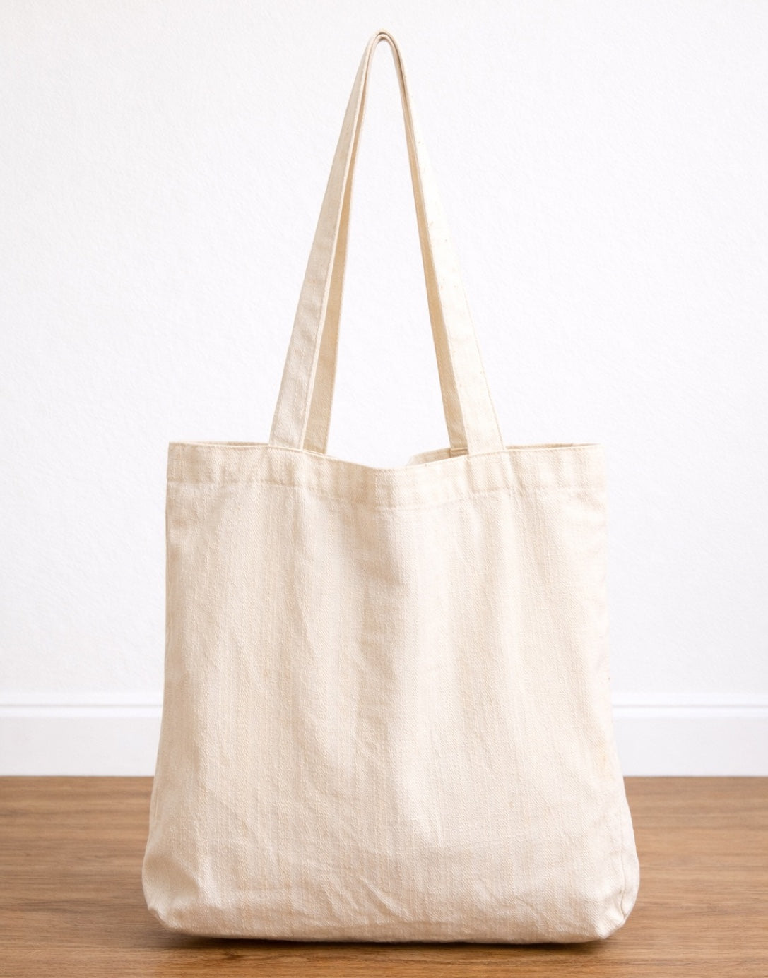 Back view of beige Tote Bag with subtle pattern on a wooden surface.