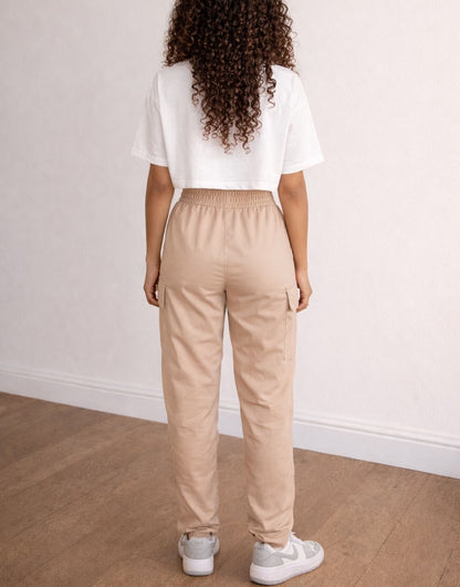 Back view of woman wearing a white crop top and beige Elastic Waist Cargo Pants on a plain background.