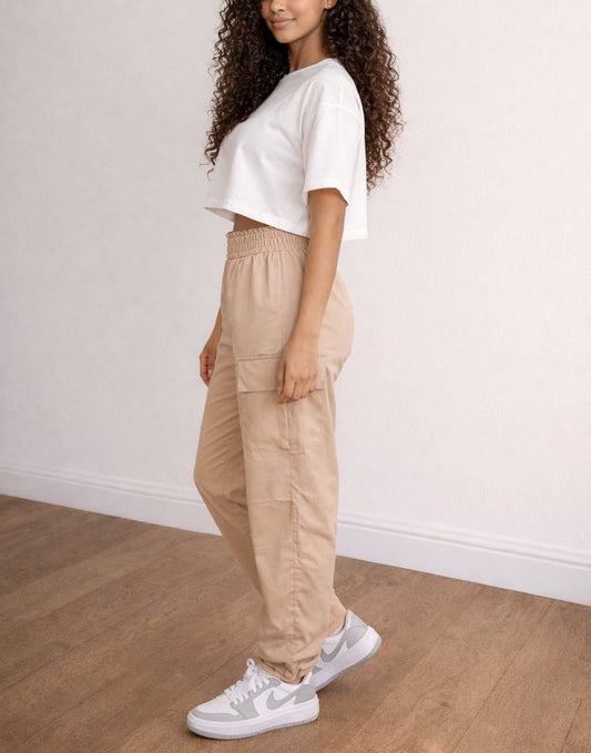 Side view of woman wearing a white crop top and beige Elastic Waist Cargo Pants on a plain background.