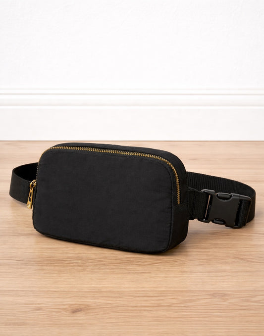 Side view of black Fanny Pack on a wooden surface with a white background