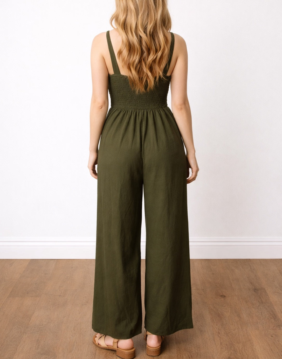 Back view of woman wearing a green Front Twist Shoulder Strap Overall Jumpsuit with a cutout design on a white background.