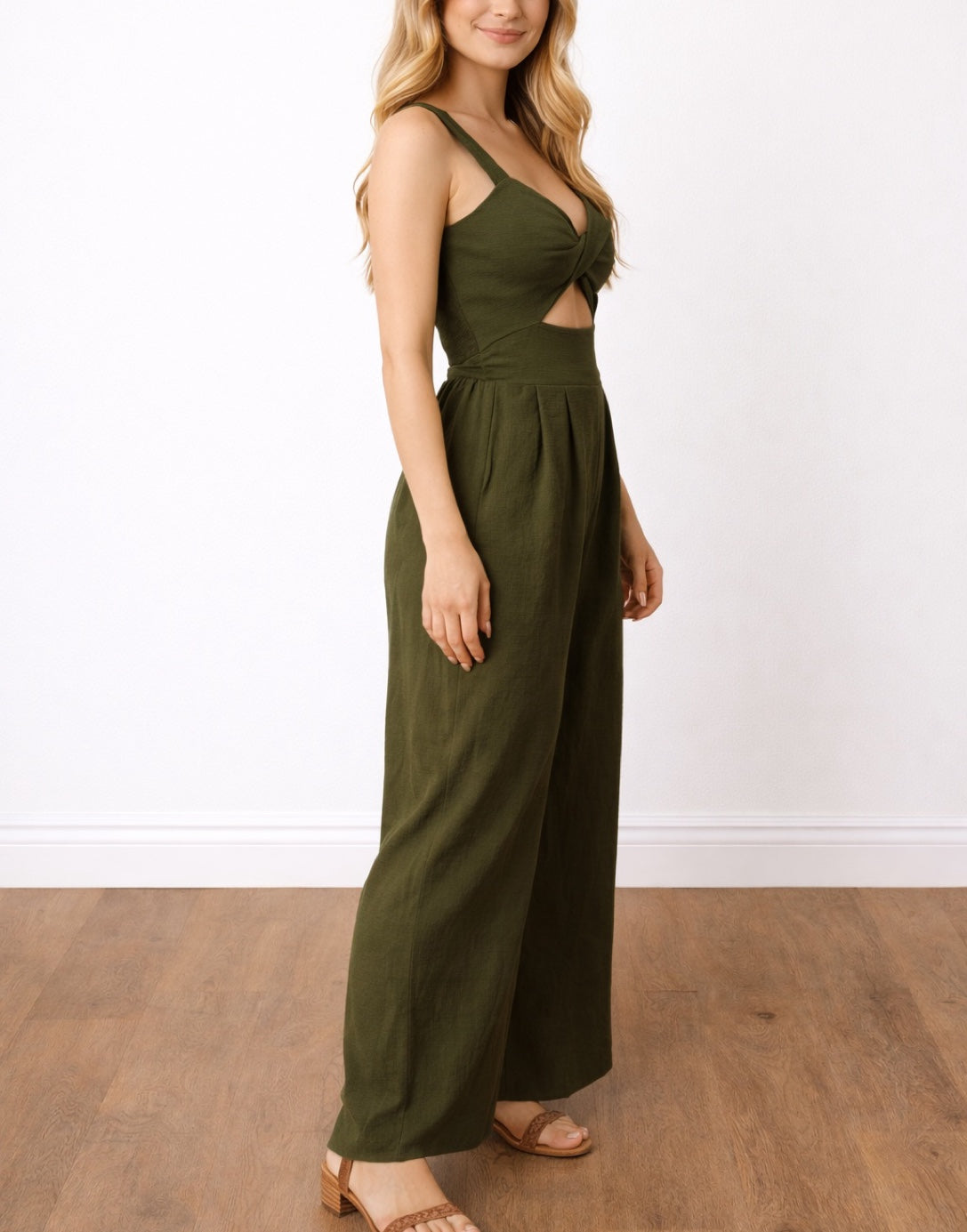 Side view of woman wearing a green Front Twist Shoulder Strap Overall Jumpsuit with a cutout design on a white background.