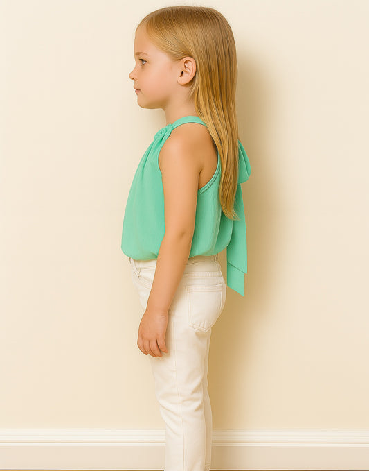 Side view of young girl wearing a mint green Halter Top and white pants against a plain background.