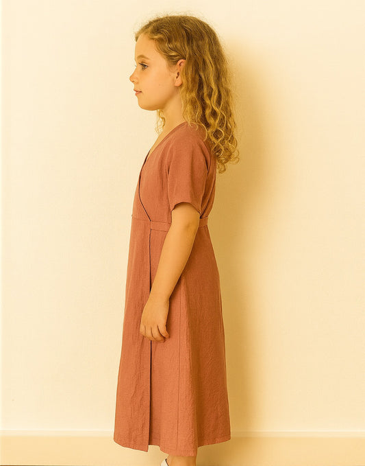 Side view of young girl wearing a rust-colored Kimono Sleeve Wrap Maxi Dress against a beige background.