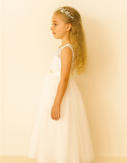 Side view of young girl in a white Lace Inset Mesh Hem Party Dress standing in a room with a couch and plant in the background.