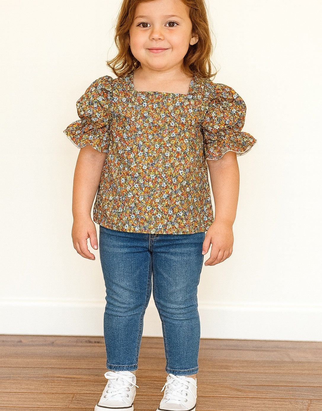 Child wearing a floral Puff Sleeve Blouse and blue jeans on a plain background