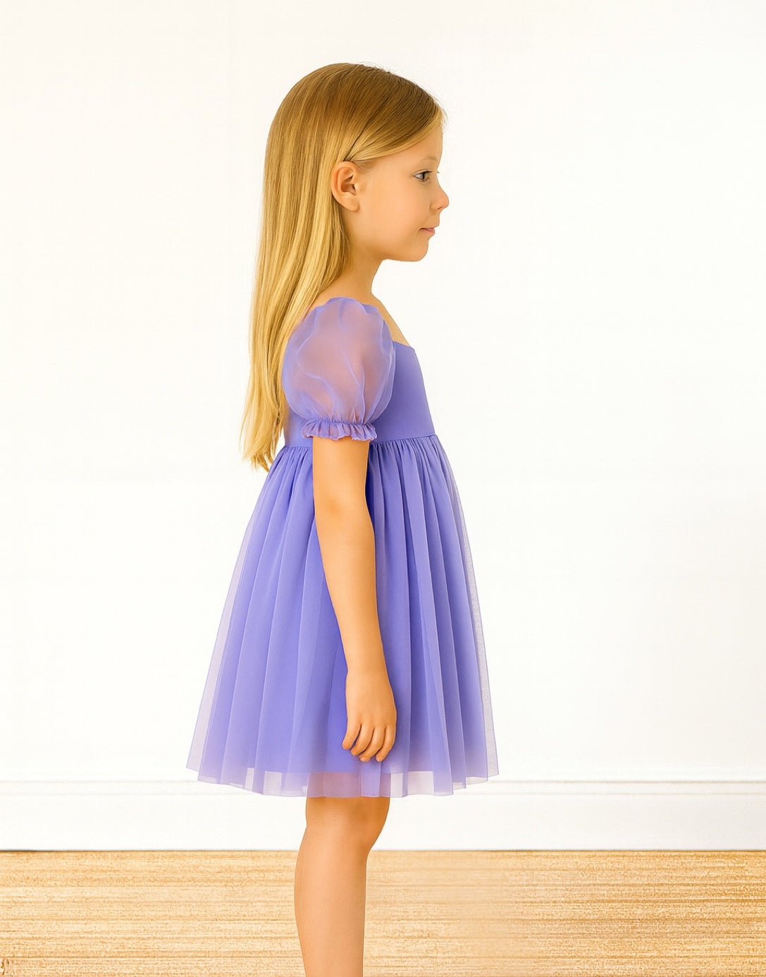 Side view of young girl wearing a purple Puff Sleeve Square Neck Dress standing on a wooden floor with a white background