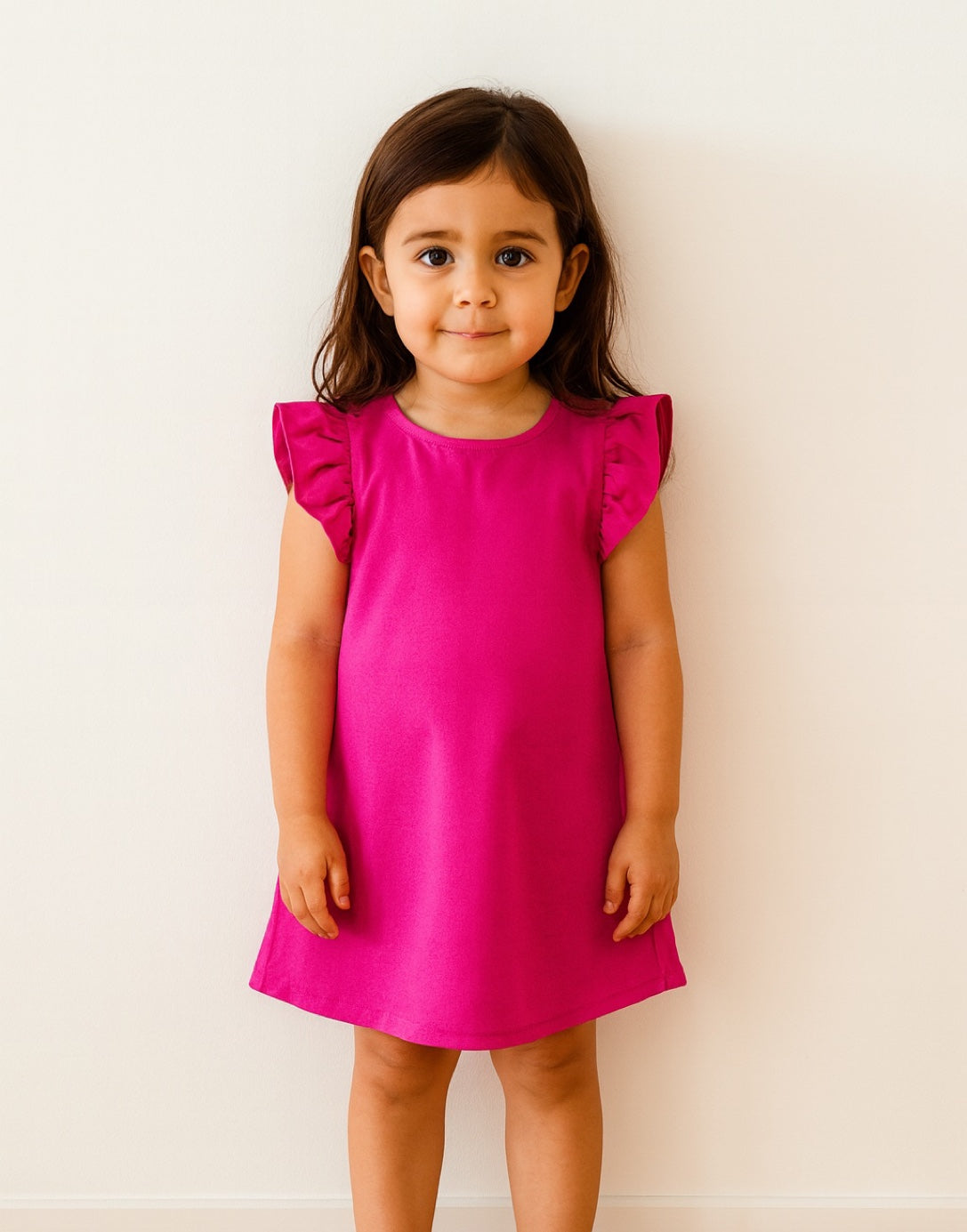 Young girl wearing a bright pink A-Line Dress with ruffled sleeves against a white background