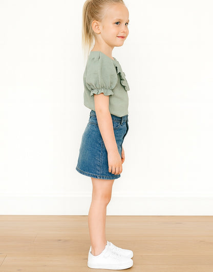 Side view of young girl wearing a green Ruffle Trim Puff Sleeve Blouse and denim skirt on a white background