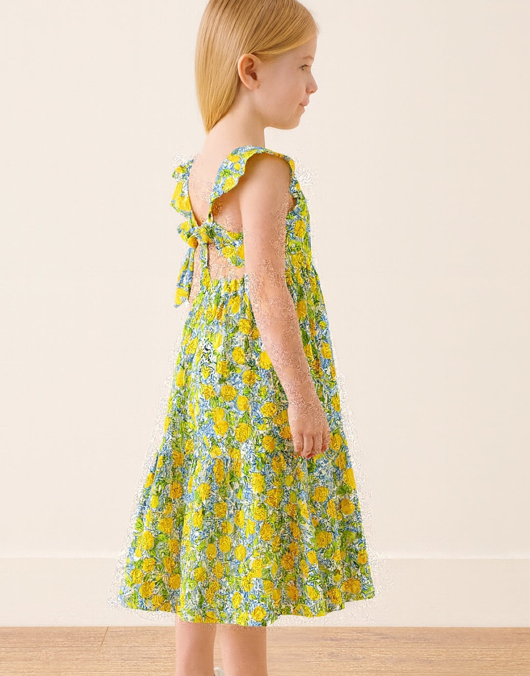 Side view of girl wear a blue and yellow floral print Square Neck Ruffled Sleeve Maxi Dress with a plain background.