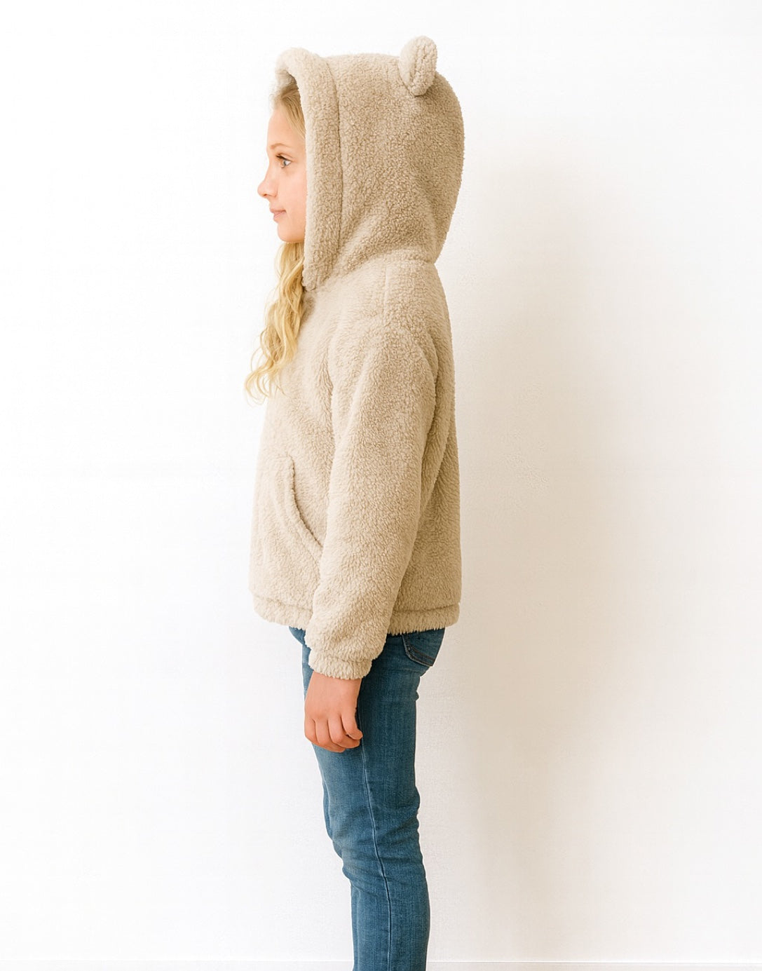 Side view of child wearing a beige fleece Teddy Ear Hooded Jacket with bear ears on a white background.