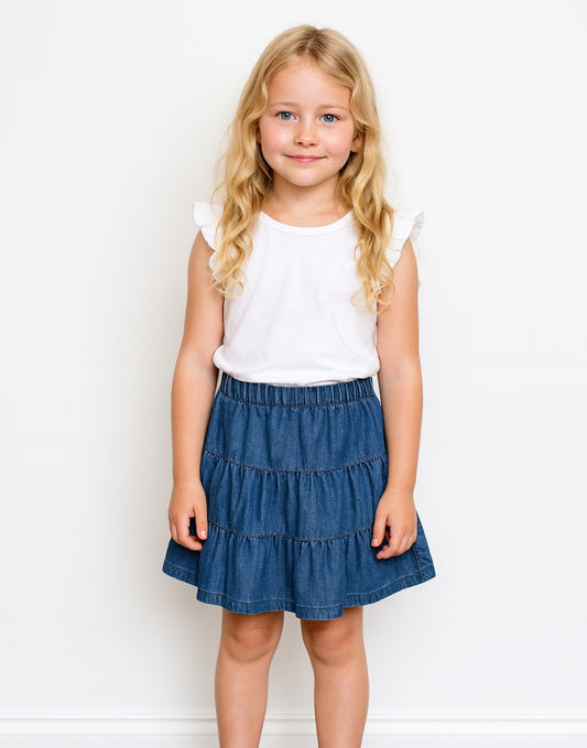 Young girl wearing a white top and blue denim Tiered Mini Skirt on a white background