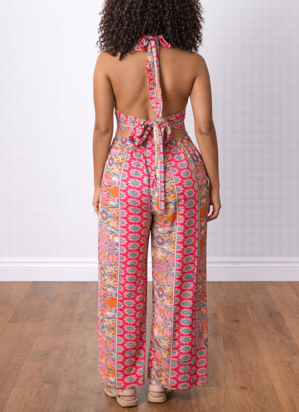Back view of woman wearing a colorful patterned Halter Crop Top and Wide Leg Pants Set on a wooden floor.