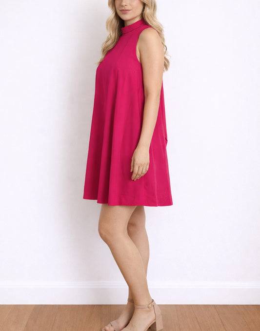 Side view of woman wearing a bright pink Halter Tie Back Dress against a white background.