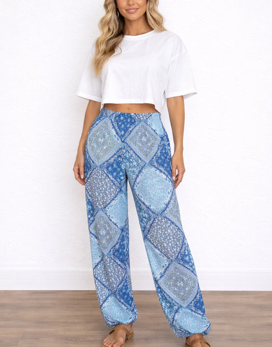 Woman wearing blue patterned Harem Pants and a white top on a white background