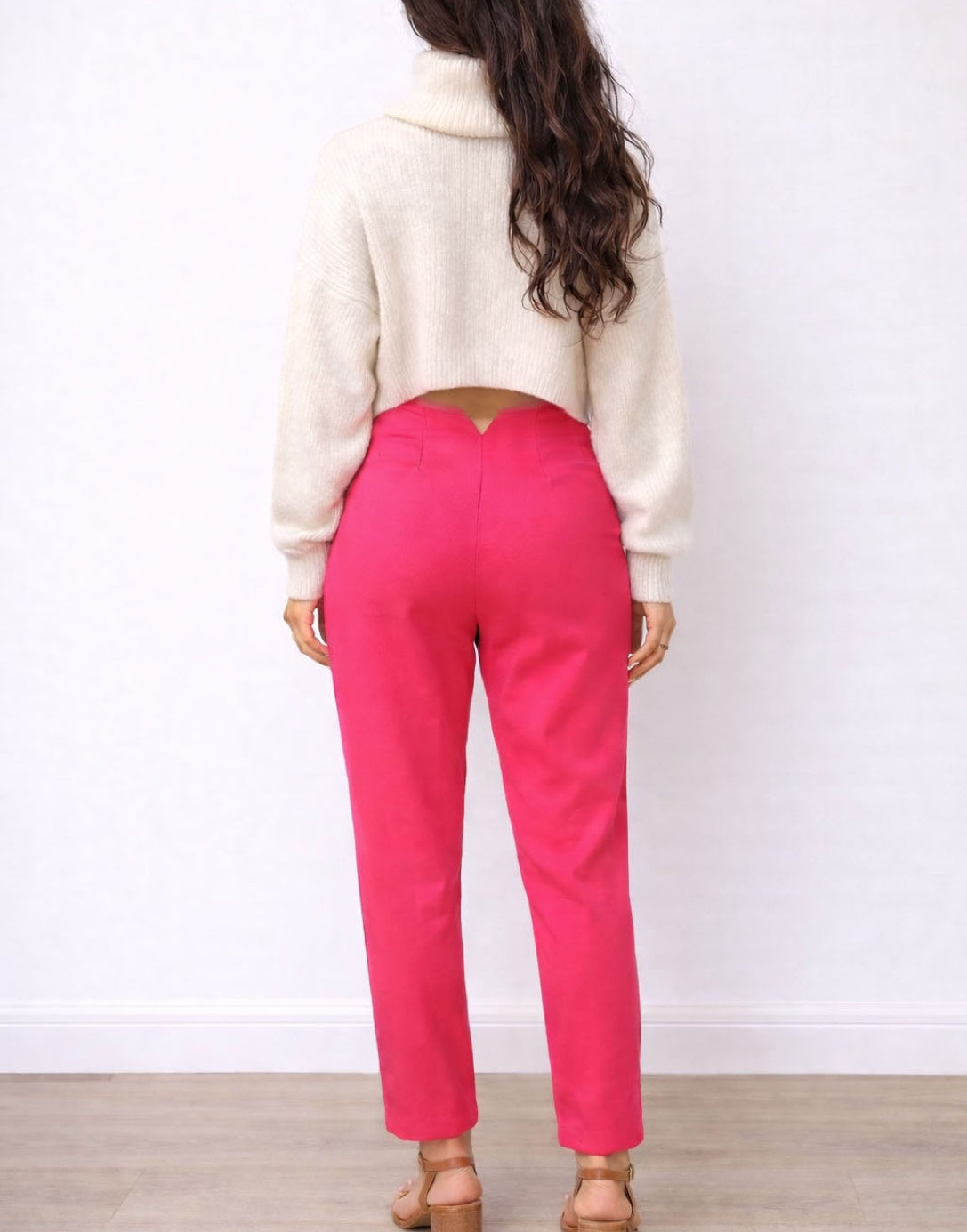 Back view of woman wearing a white sweater and bright pink High Waist Straight Leg Pants on a plain background.