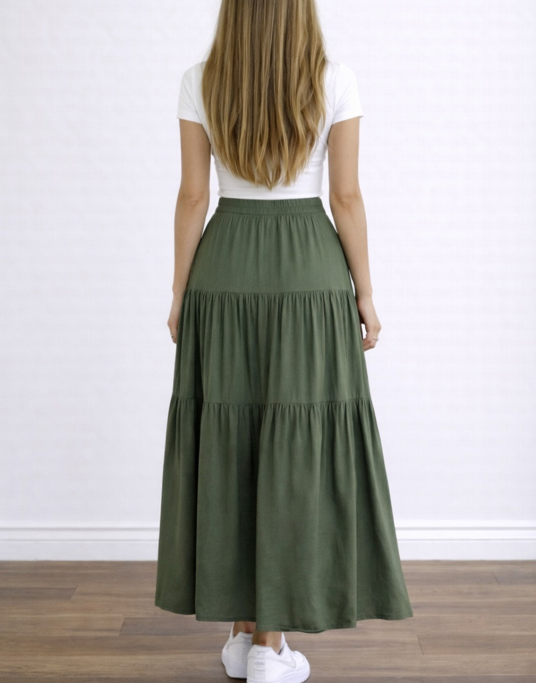 Back view of woman wearing a white top and green High Waist Tiered Hem Maxi Skirt on a plain background.